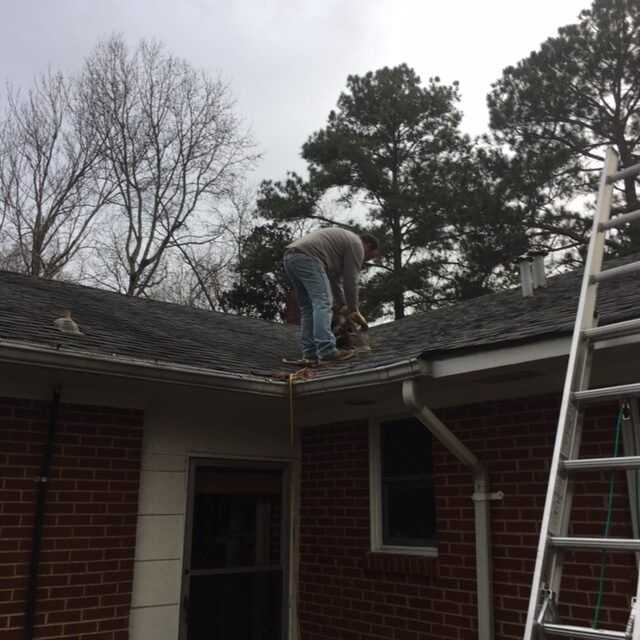 Man repairing roof with tools and ladder on a cloudy day.